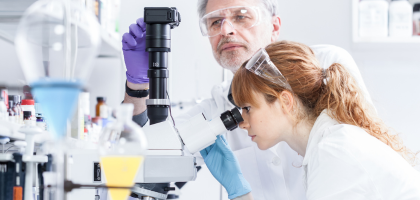 Dwoje naukowców korzysta z mikroskopu.