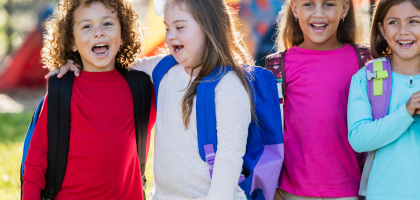 Grupa uśmiechniętych dzieci w kolorowych strojach.